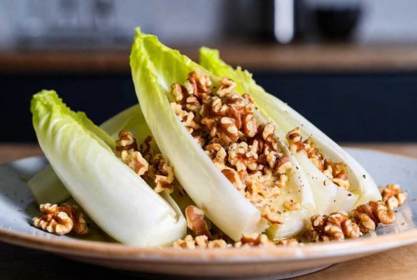 Feuilles d'endive dans une assiette recouvertes de noix