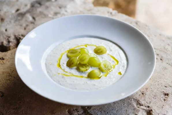 Assiette blanche d'ajo blanco avec un filet d'huile d'olive et des raisins verts coupés en deux