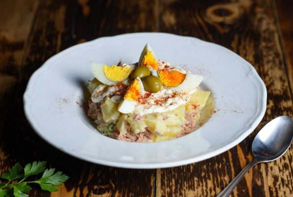 Petite assiette d'ensaladilla rusa avec sa garniture d’œuf dur et d'olives, saupoudrée de pimentón